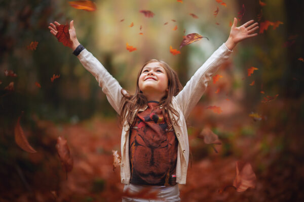image of a girl throwing autumn leaves by Willie Kers