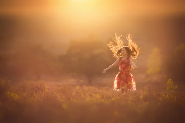 Canon sunset portrait of a childhood girl sunbathing in the open field with a pink sky by Willie Kers
